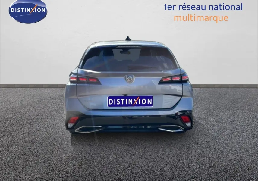 Vue arrière d'une Peugeot 308 SW Hybrid gris Artense métal, mettant en valeur ses feux arrière étirés et son double échappement intégré.