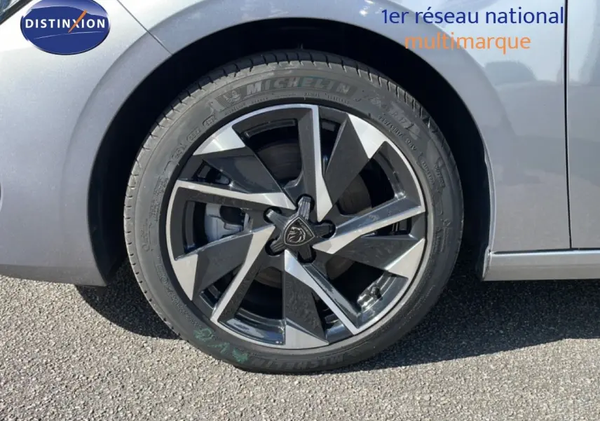 Gros plan sur la roue avant droite d'une Peugeot 308 SW gris Artense métal avec jante alliage bicolore distinctive.