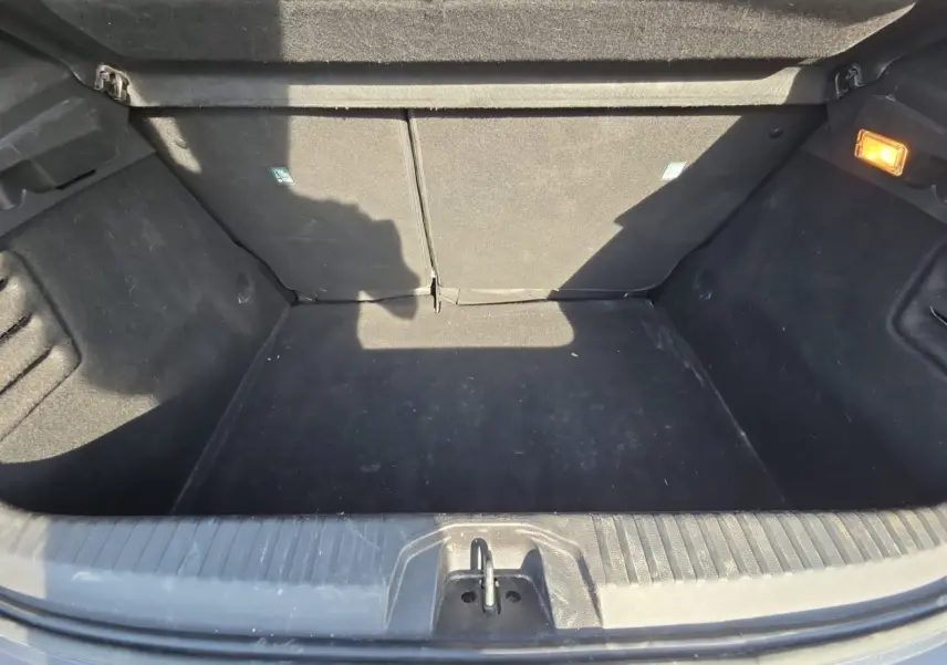 Coffre ouvert vu de face d’une Renault Clio V gris foncé métal, montrant un espace de chargement propre et éclairé.
