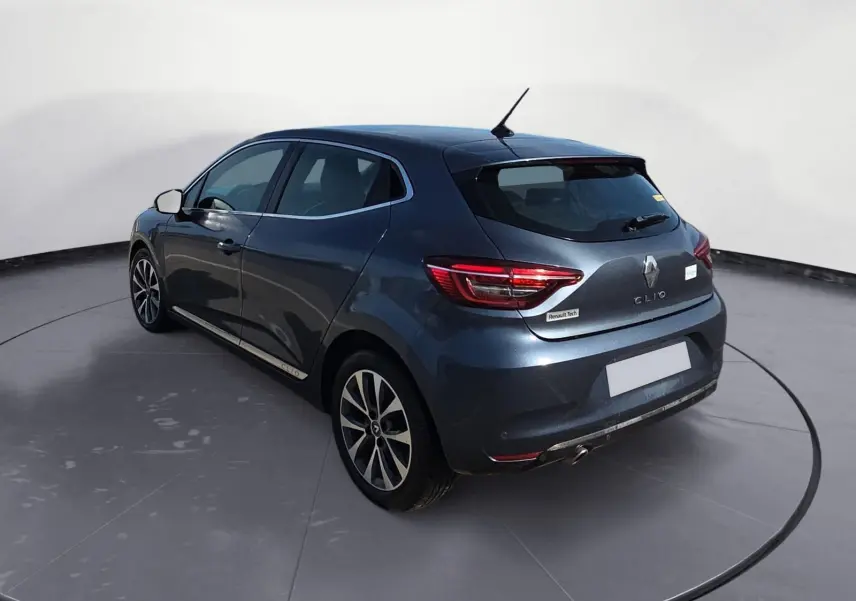 Renault Clio V TCE 90 2021 gris foncé métal vue 3/4 arrière droit avec jantes alliage et feux LED allumés.
