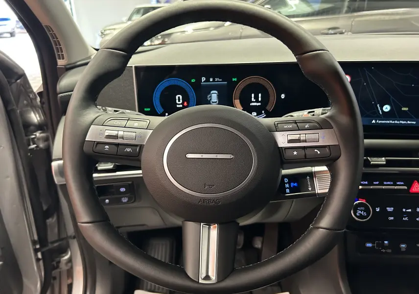 Vue rapprochée du volant noir et du tableau de bord numérique du Hyundai Tucson 2025 hybride en intérieur.