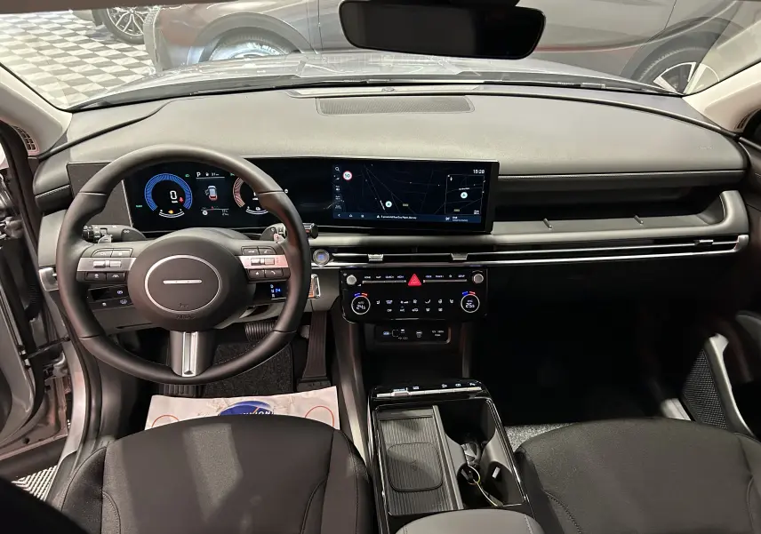 Intérieur du Hyundai Tucson 2025 en Shimmering Silver, vue frontale du tableau de bord avec écran large et volant multifonction.