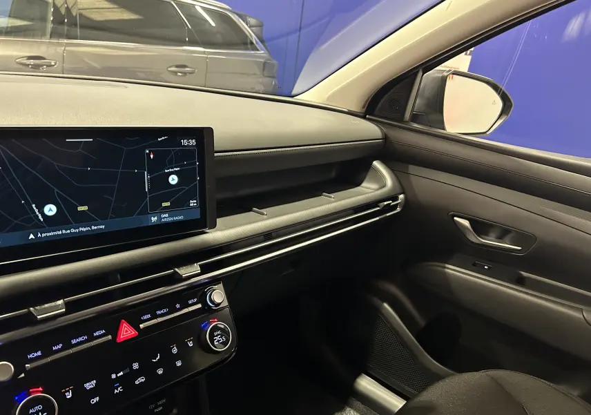 Intérieur côté passager du Hyundai Tucson 2025, tableau de bord moderne avec écran tactile et finitions noires élégantes.