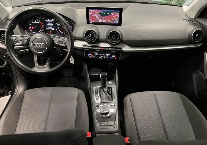 Vue intérieure avant de l'Audi Q2 2022 noir, avec tableau de bord, volant cuir multifonction et écran navigation central.