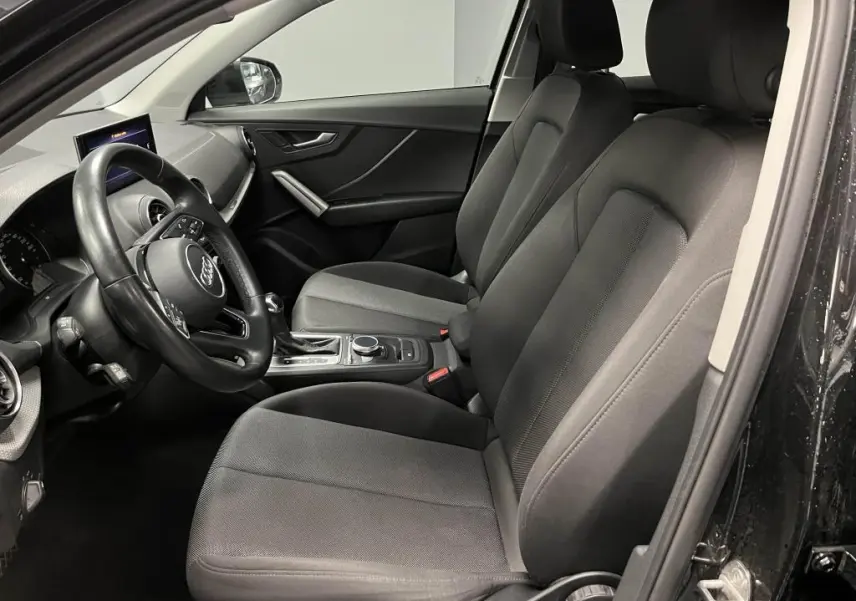 Intérieur avant de l'Audi Q2 noir, vue côté gauche montrant sièges tissu Skript et volant multifonction cuir.