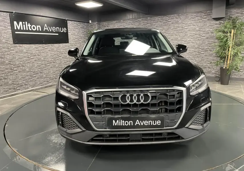 Audi Q2 Business line noir brillant vue de face dans un showroom avec calandre hexagonale et phares LED.