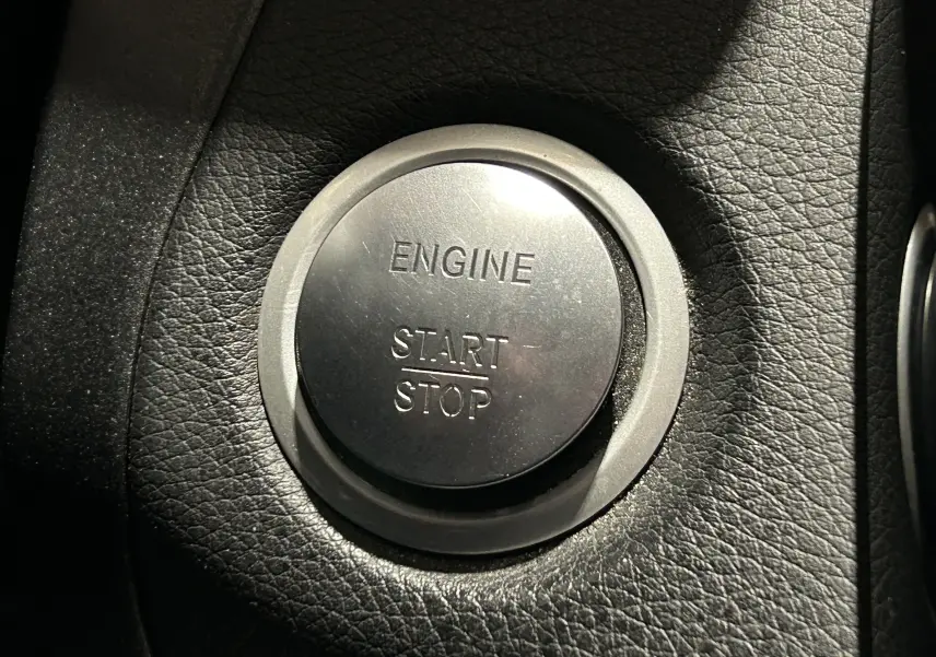 Bouton rond argenté "Engine Start Stop" sur tableau de bord en cuir noir d'une Mercedes Classe C 200d 2018.