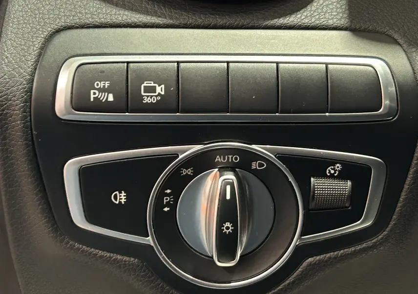 Gros plan sur les commandes d'éclairage et caméra 360° de la Mercedes Classe C 200d bleue, intérieur noir.