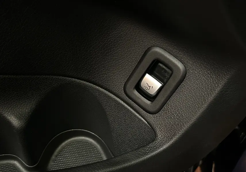 Gros plan sur le bouton d'ouverture électrique du coffre dans l'habitacle d'une Mercedes Classe C 200d bleu 2018.