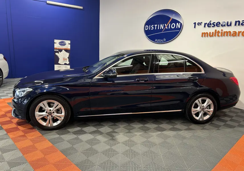 Profil latéral droit d'une Mercedes Classe C 200d bleu foncé dans un showroom avec sol gris et orange.