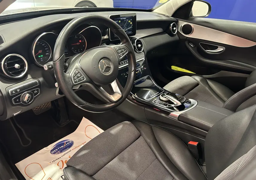 Intérieur avant gauche d'une Mercedes Classe C 200d bleu, volant cuir multifonction et écran GPS central visible.