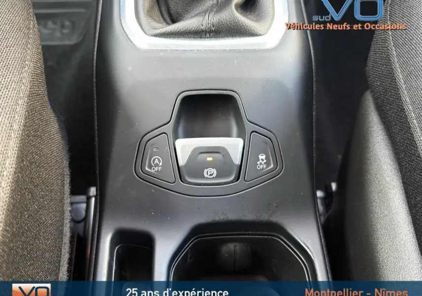 Gros plan sur la console centrale noire du Jeep Renegade blanc, mettant en valeur le frein à main électrique et la commande Start/Stop.