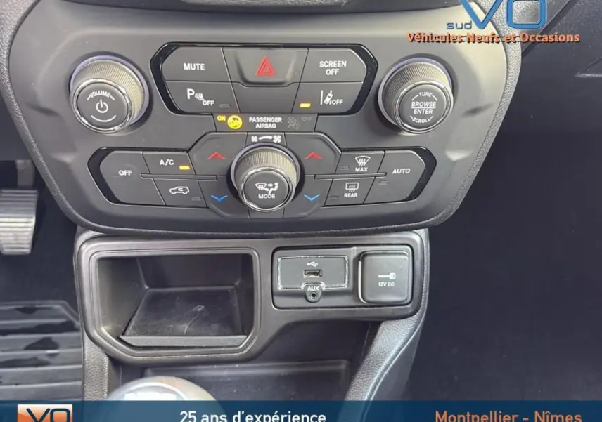 Vue rapprochée de la console centrale du Jeep Renegade blanc 2020, montrant les commandes climatisation et connectivité.