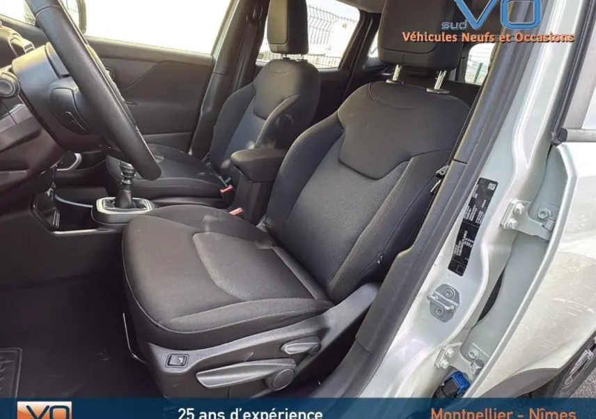 Intérieur avant droit du Jeep Renegade blanc 2020, sièges noirs avec accoudoir central et boîte manuelle visible.