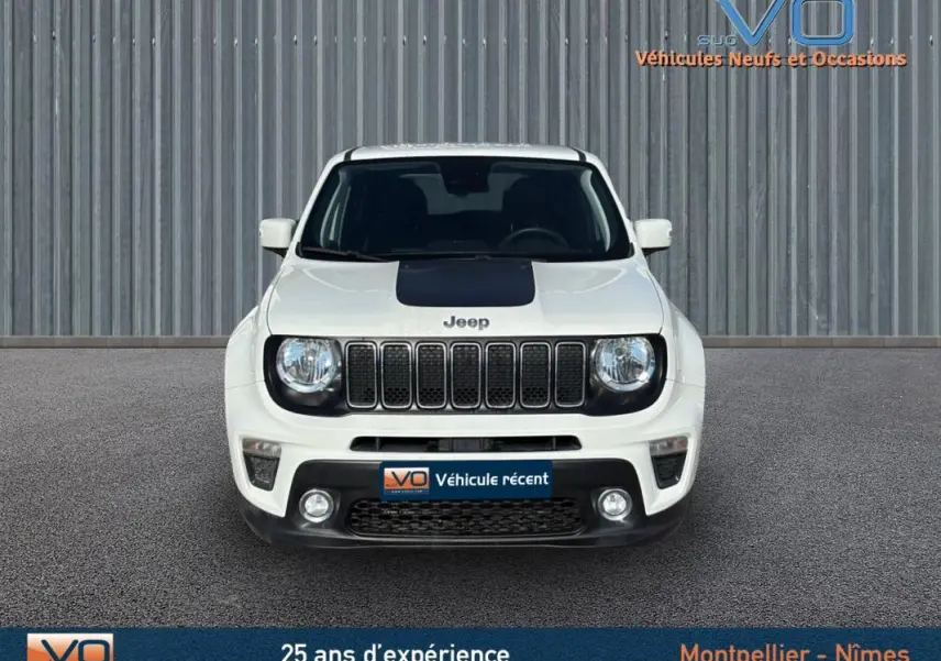 Vue frontale d'un Jeep Renegade blanc avec capot noir et calandre distinctive, stationné devant un mur métallique.