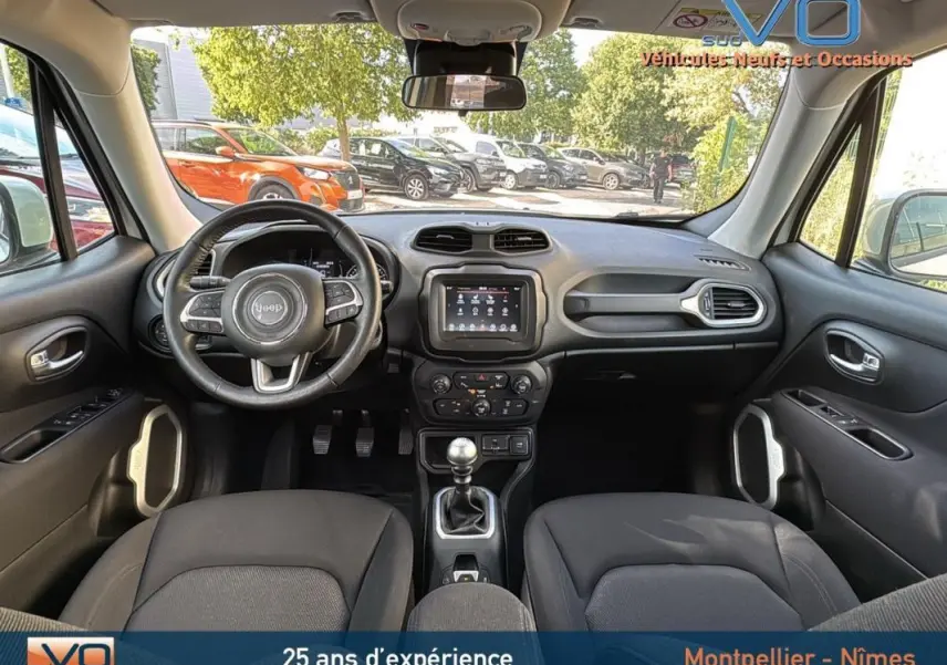 Vue intérieure avant du Jeep Renegade 2020 blanc, volant multifonction, écran tactile et boîte manuelle visibles.