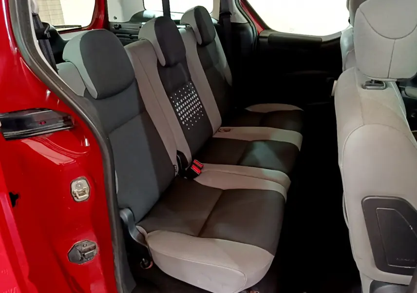 Vue intérieure des sièges arrière bicolores gris et noir du Citroën Berlingo rouge, porte arrière ouverte côté gauche.