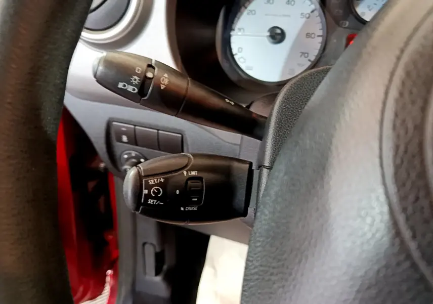 Gros plan sur les commandes de régulateur et feux du tableau de bord d'un Citroën Berlingo rouge côté gauche.