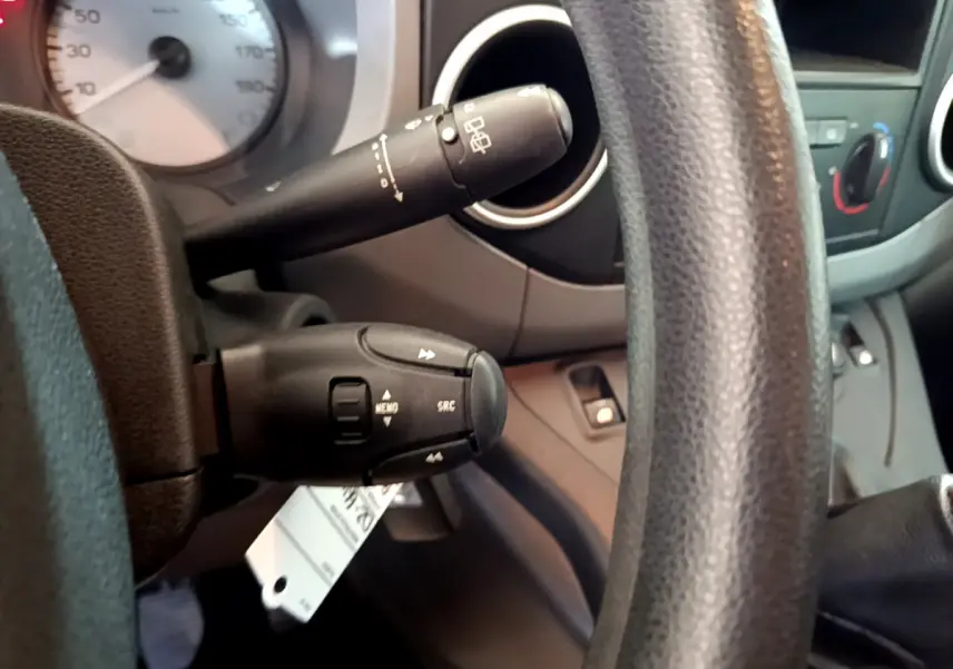 Gros plan sur la colonne de direction et commandes au volant du Citroën Berlingo 2016, intérieur gris et noir.