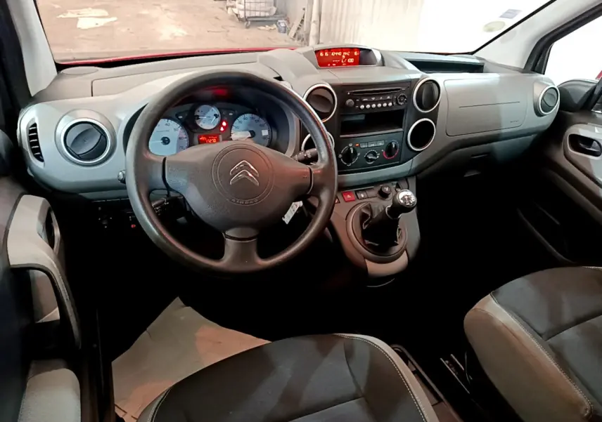 Vue intérieure avant du Citroën Berlingo 2016, tableau de bord gris avec volant noir et levier de vitesses manuel.