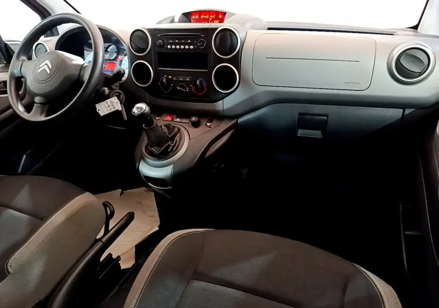 Intérieur du Citroën Berlingo 2016 côté conducteur, tableau de bord gris avec volant noir et levier de vitesses manuel.