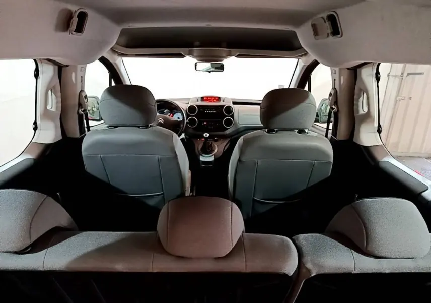 Vue intérieure arrière du Citroën Berlingo rouge 2016, montrant les sièges avant et le tableau de bord.