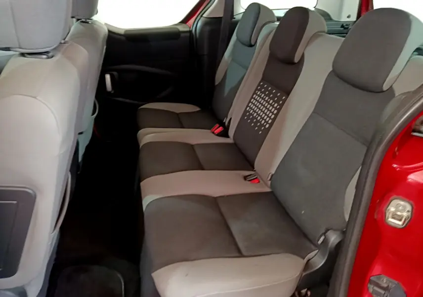 Vue latérale intérieure des sièges arrière gris et noirs du Citroën Berlingo rouge 2016, porte ouverte côté droit.