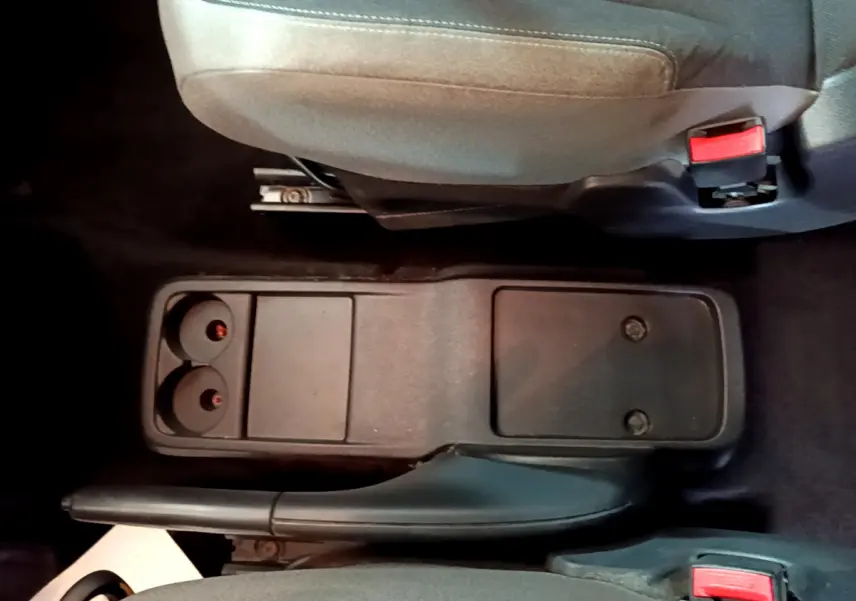 Vue rapprochée de la console centrale noire entre les sièges avant gris du Citroën Berlingo rouge 2016.