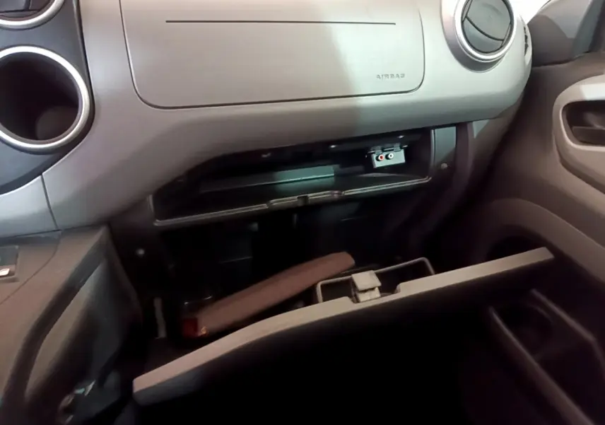 Intérieur du Citroën Berlingo 2016, vue sur la boîte à gants ouverte côté passager avec détails du tableau de bord gris.