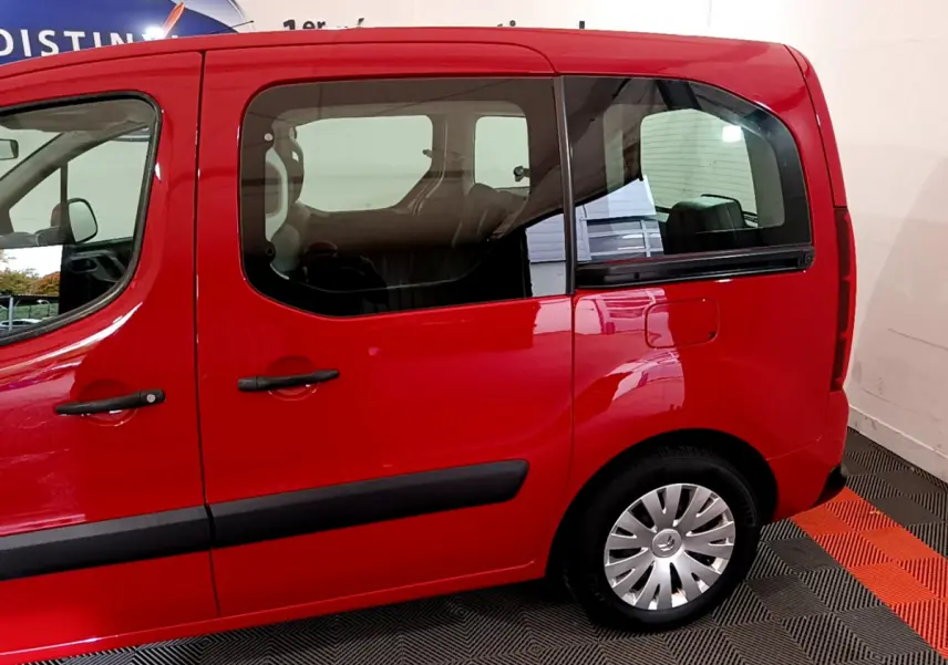 Vue latérale côté droit d'un Citroën Berlingo rouge 2016 avec portes coulissantes et jantes acier à enjoliveurs.
