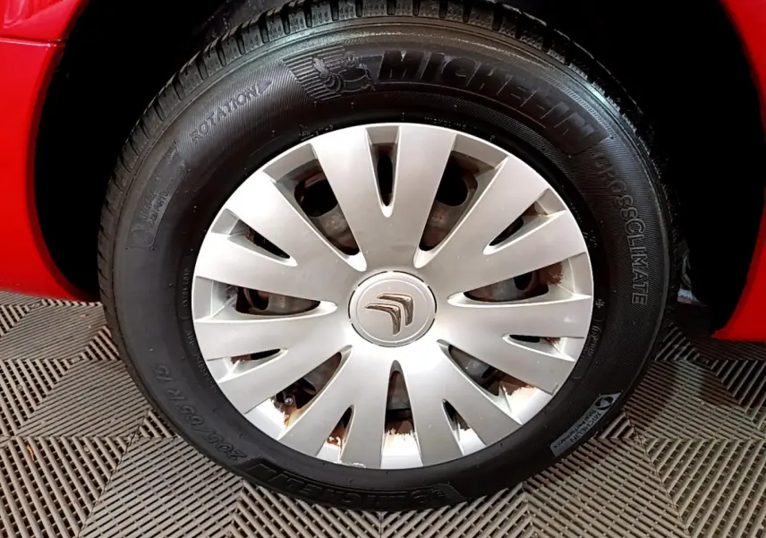 Gros plan sur la roue avant gauche rouge d’un Citroën Berlingo 2016 avec enjoliveur argenté et pneu Michelin.