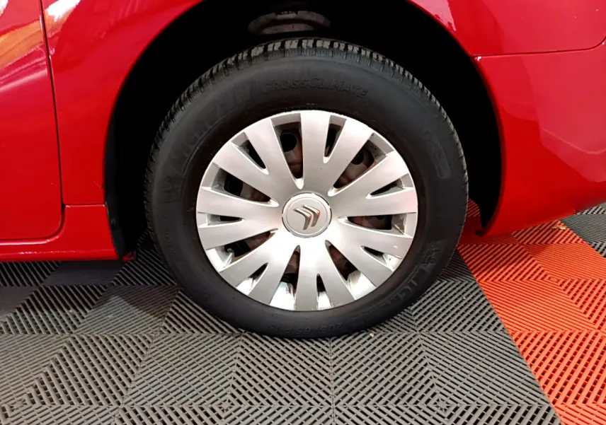 Gros plan sur la roue avant gauche d’un Citroën Berlingo rouge de 2016 avec enjoliveur argenté et pneu Michelin.