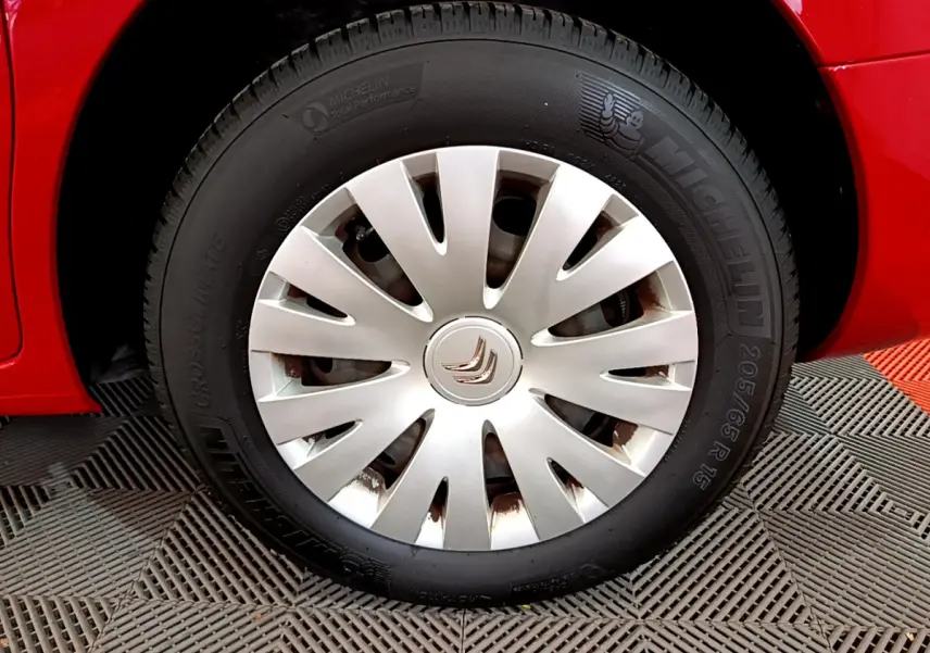 Gros plan sur la roue avant droite rouge d’un Citroën Berlingo 2016 avec enjoliveur argenté et pneu Michelin.