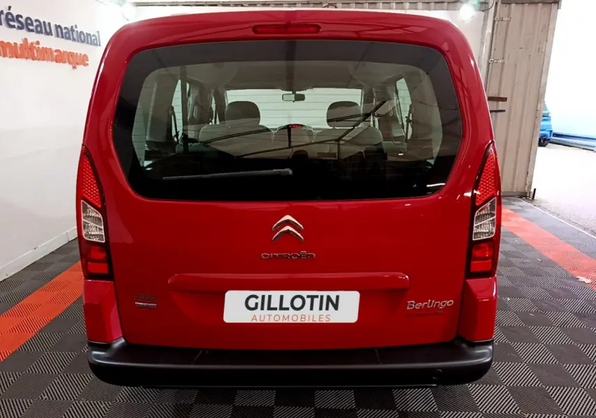 Vue arrière d'un Citroën Berlingo rouge 2016 avec hayon vitré et logo visible sur fond d'intérieur showroom.