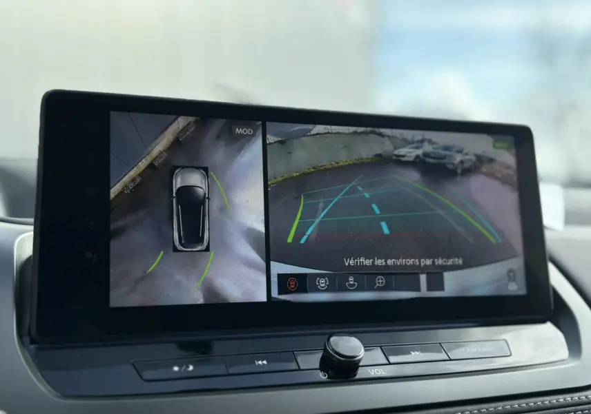 Écran intérieur du Nissan Qashqai blanc nacré montrant la caméra 360° et la vue arrière avec aides au stationnement.