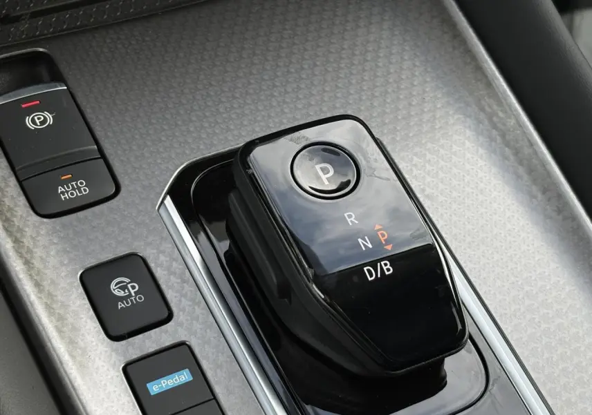 Gros plan sur la commande de boîte automatique noire et les boutons e-Pedal et frein à main dans un Nissan Qashqai blanc nacré.