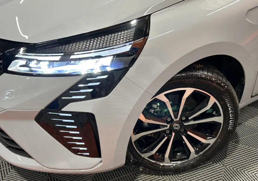 Gros plan sur l’avant droit gris Rafale métal de la Renault Clio V E-Tech avec phares LED et jante alliage distinctive.