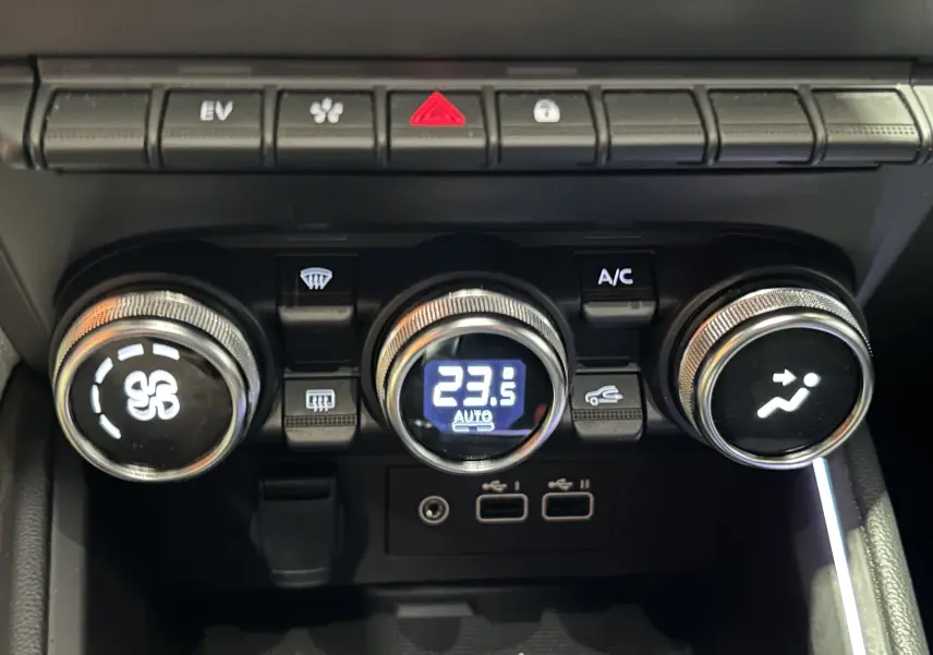 Gros plan sur la console centrale de la Renault Clio V E-Tech, montrant les commandes de climatisation digitales et boutons fonctionnels.