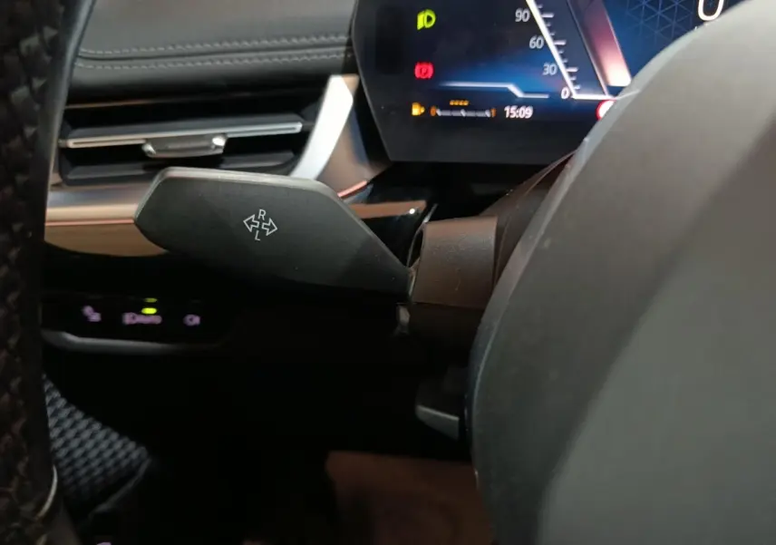 Gros plan sur le commodo de clignotant noir dans l’habitacle du BMW X1 xDrive23i M Sport 2023, tableau de bord digital visible.