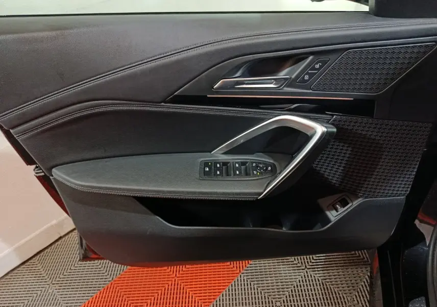 Vue rapprochée de la porte avant gauche noire du BMW X1 xDrive23i M Sport 2023 avec commandes de vitres et poignée alu.