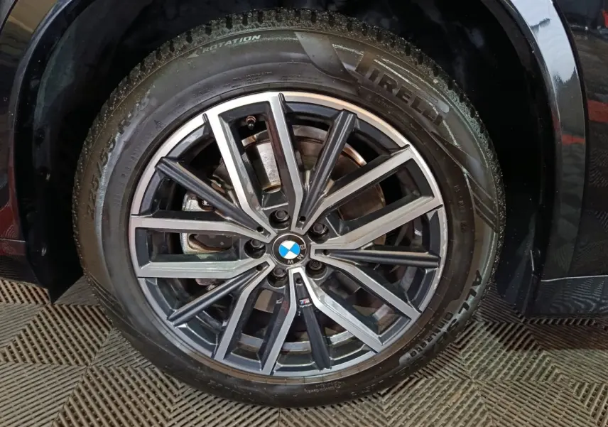 Gros plan sur la roue avant droite noire d’un BMW X1 xDrive23i M Sport avec jante alliage M distinctive.