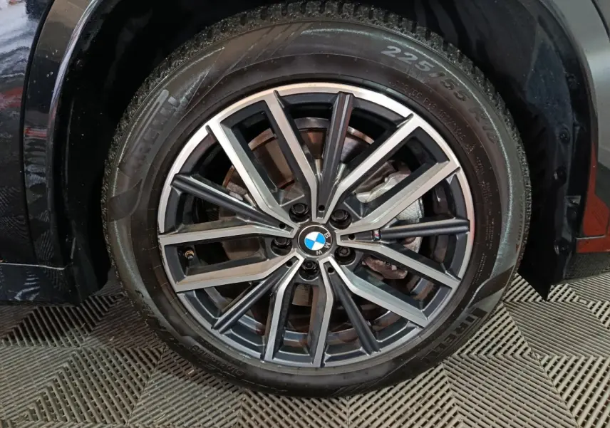 Gros plan sur la roue avant droite noire d’un BMW X1 xDrive23i M Sport 2023 avec jante alliage bicolore.