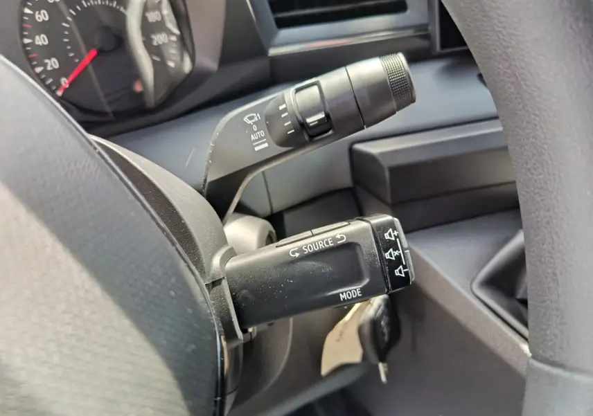 Gros plan sur les commandes au volant du Renault Master blanc, montrant les boutons source et mode sur la manette.
