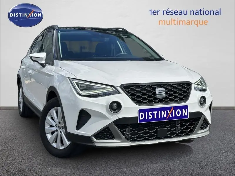 SEAT Arona blanc Nevada avec toit noir, vue 3/4 avant mettant en valeur la calandre et les phares LED.