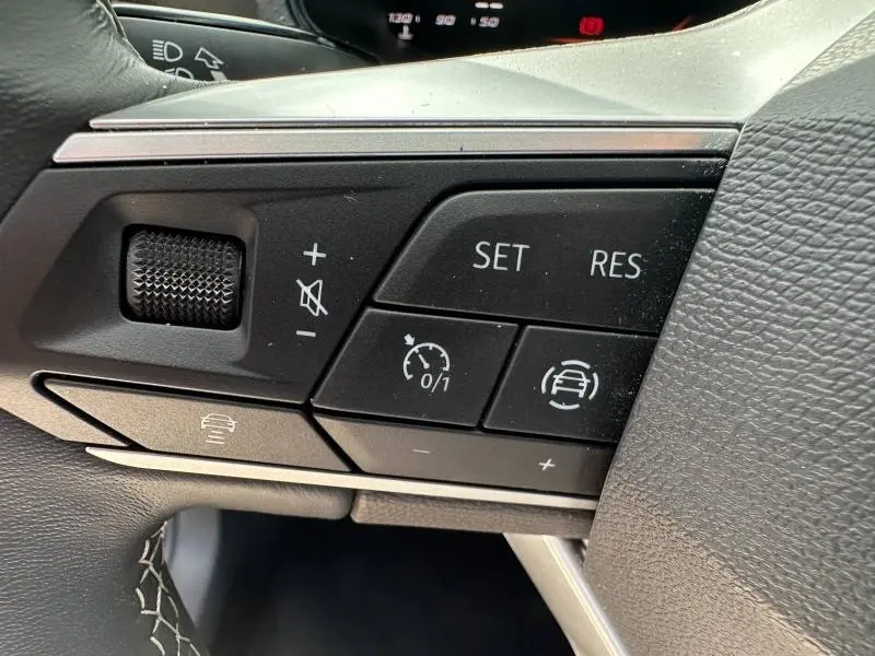 Gros plan sur les commandes noires du volant cuir multifonction du SEAT Arona 2025, côté gauche.