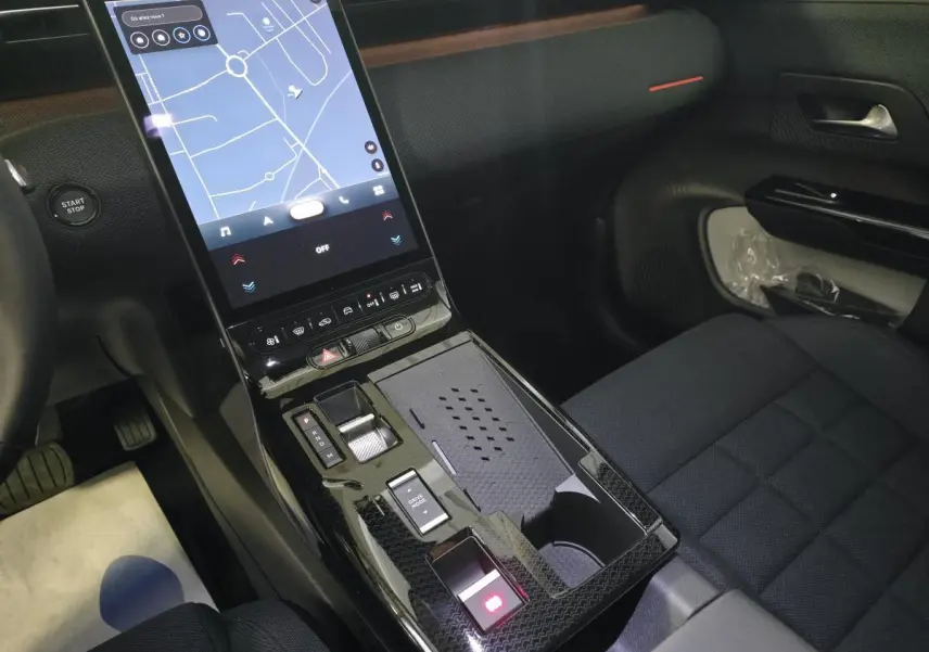 Vue intérieure centrée sur la console centrale noire brillante avec écran tactile vertical et sièges tissu bleu du Citroën C5 Aircross.