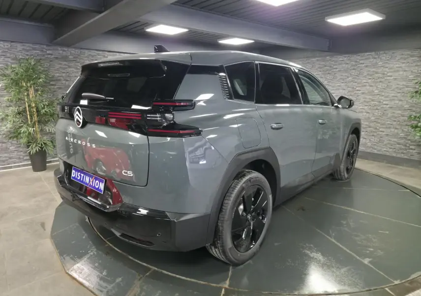 Vue 3/4 arrière droite d'un Citroën C5 Aircross gris métallisé avec toit noir et jantes noires.