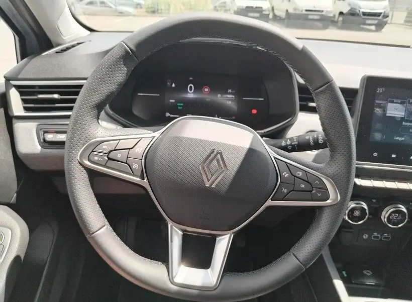 Vue rapprochée du volant noir perforé de la Renault Clio V TCE 90 Evolution 2026 avec tableau de bord numérique et commandes intégrées.