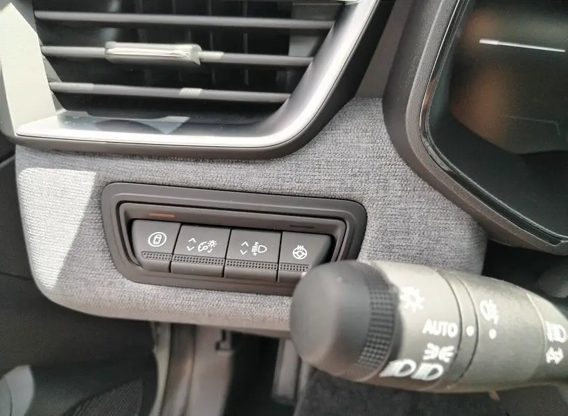 Gros plan sur les commandes d’éclairage et de réglage du tableau de bord gris clair de la Renault Clio V TCE 90 Evolution.