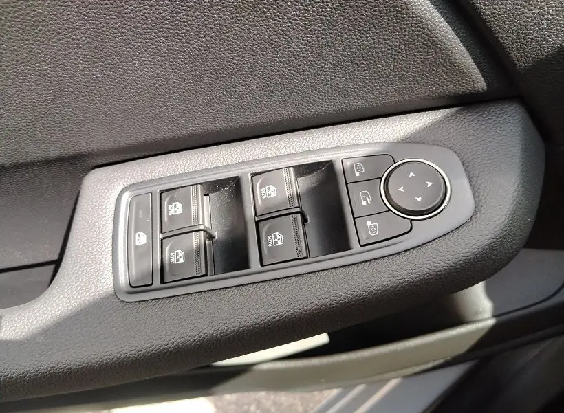 Gros plan sur les commandes de lève-vitres et rétroviseurs côté gauche intérieur de la Renault Clio V gris Rafale.
